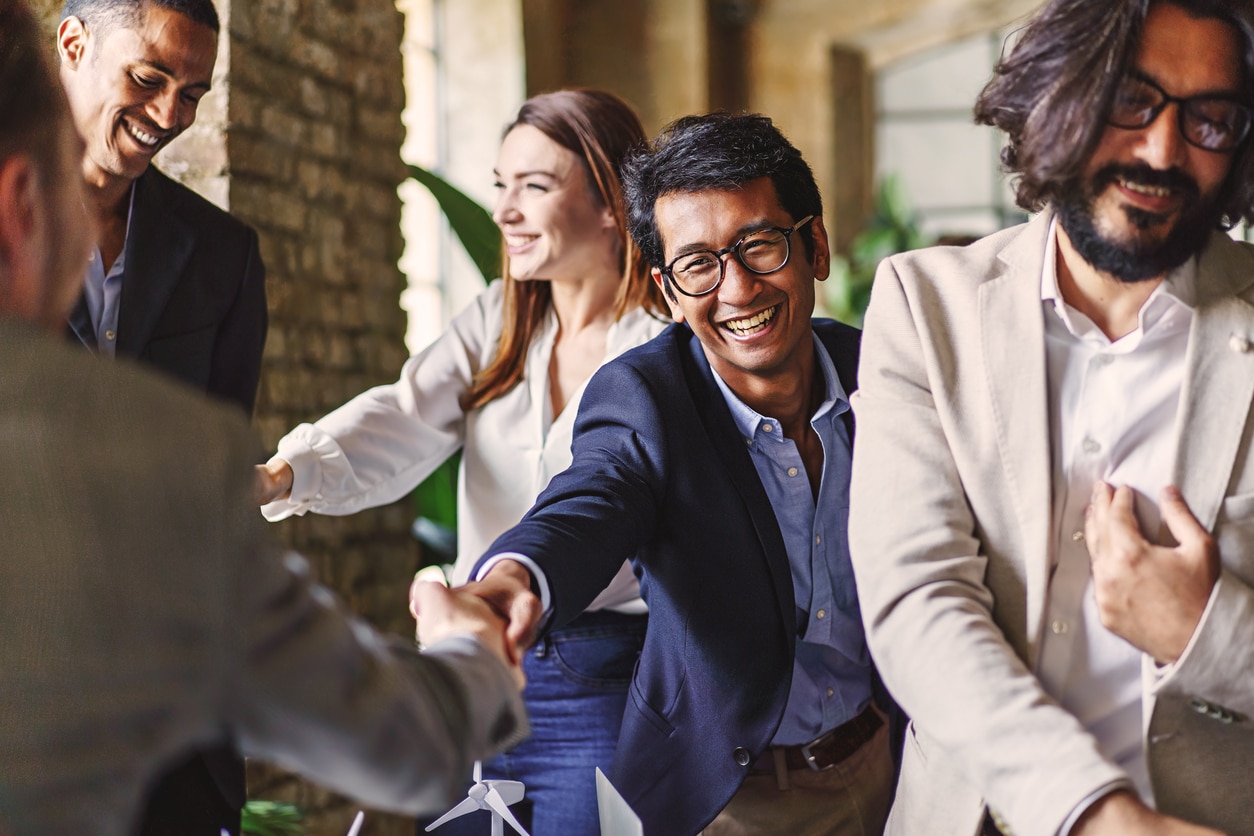 Several sets of business professionals enact what they’ve learned about how to network, shaking hands with each other and smiling.