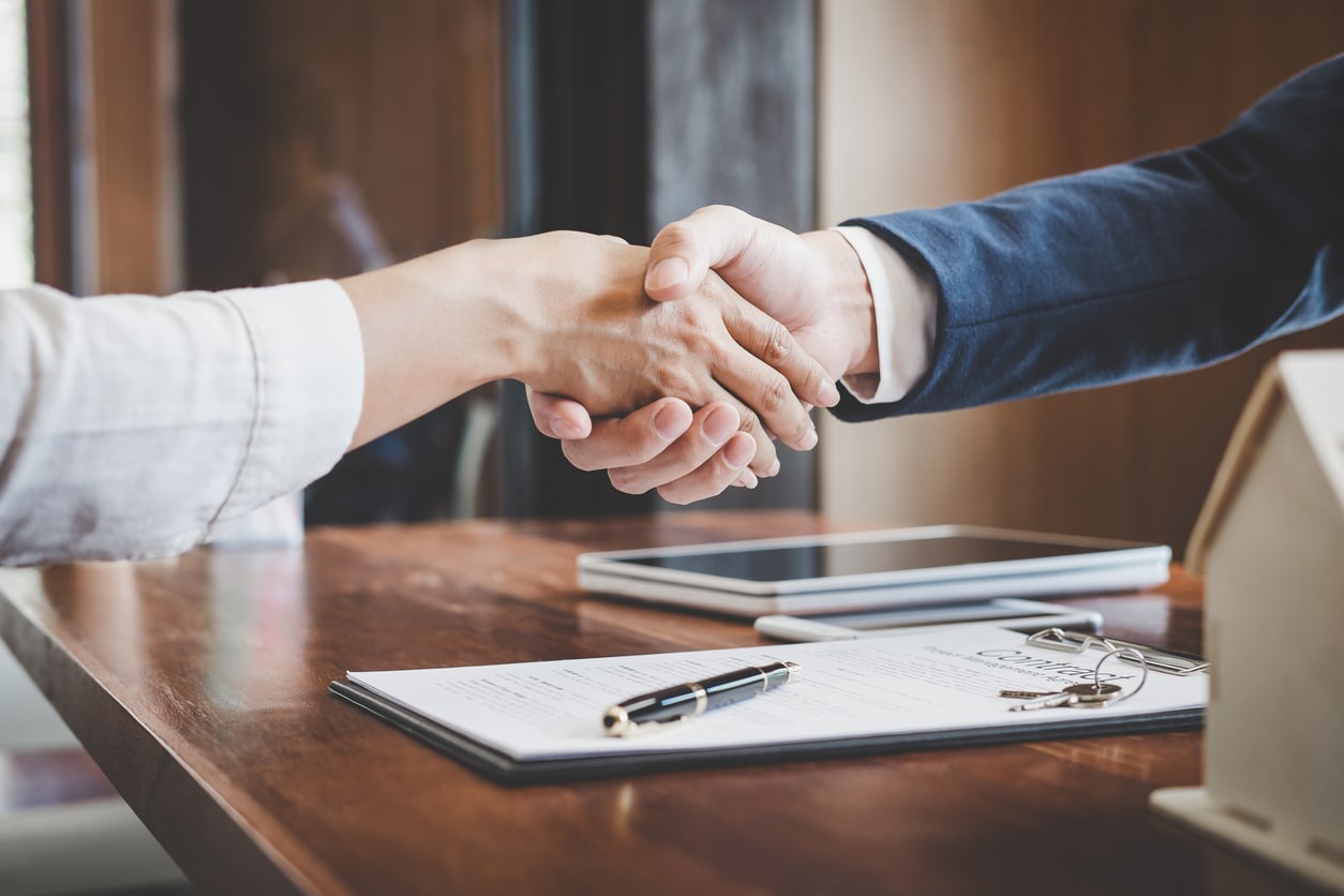 A man and woman shake hands over a successful business agreement thanks to a concrete business exit plan.